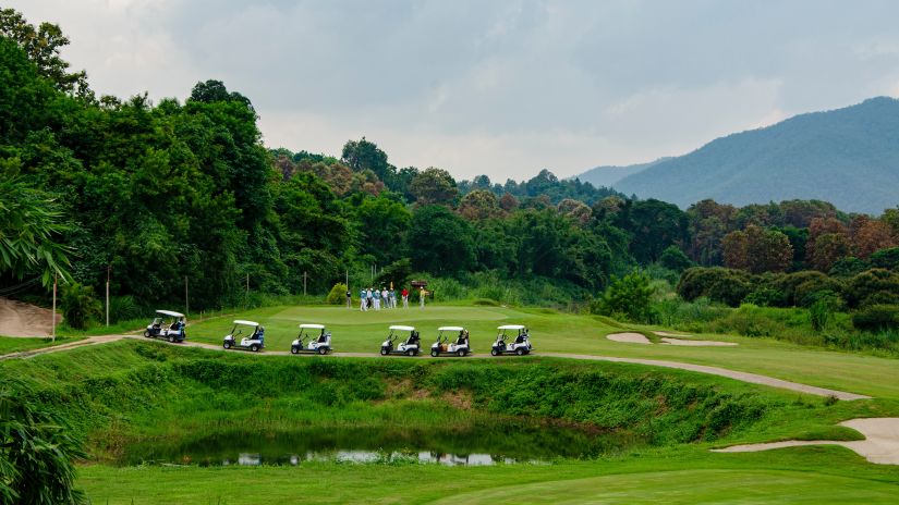 lush green golf course amidst the mountain with a few golf carts