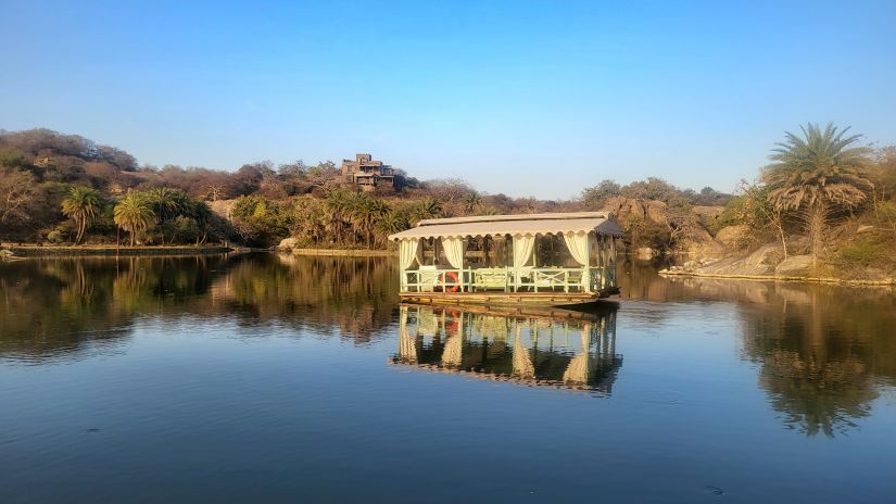 a boat flowing in the river near Chunda Shikar Oudi, Udaipur with the forest in the background