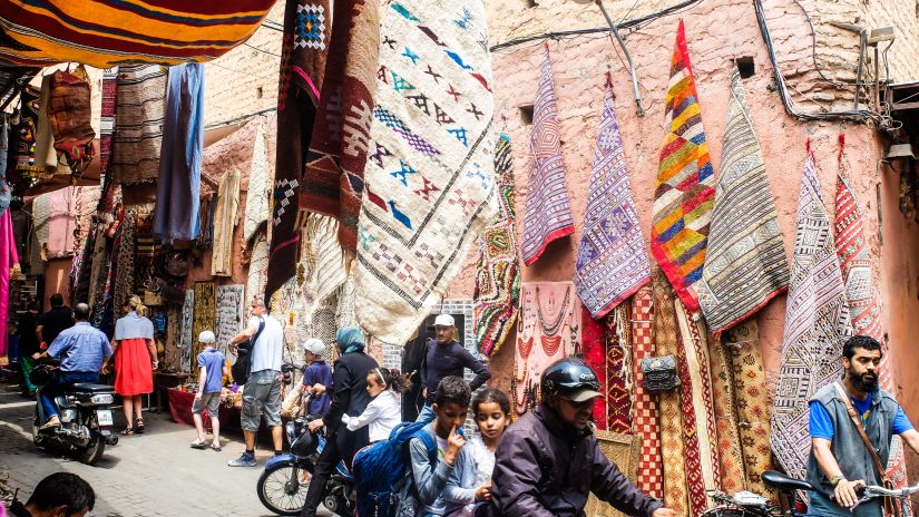 a street market with people moving on the road and different things being sold by vendors