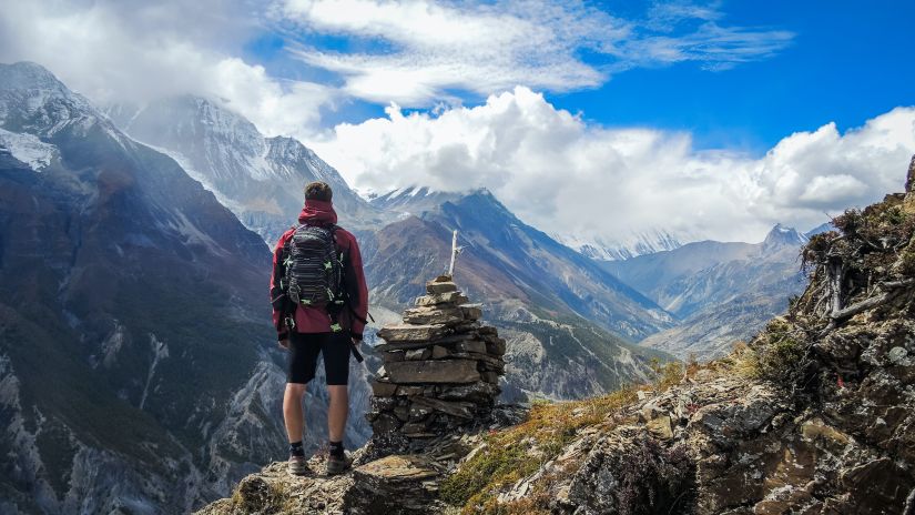 A person looking at a mountain view from atop a hill after a trek