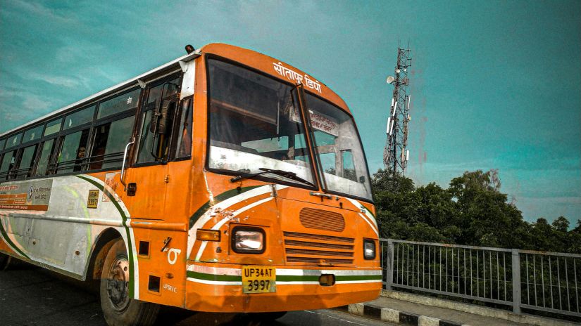 A orange coloured bus travelling on a road