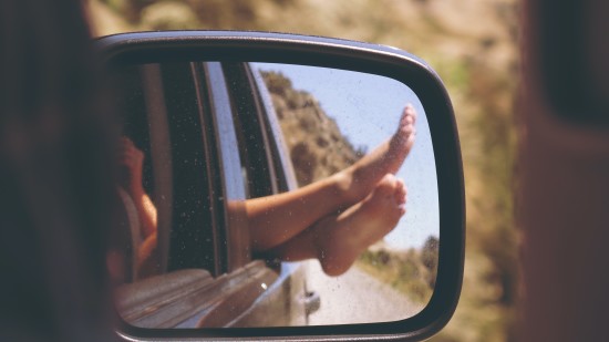 car mirror's side view of a person's feet out the window