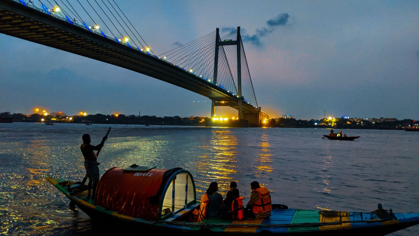 Howrah bridge with a boat passing by in Hooghly river