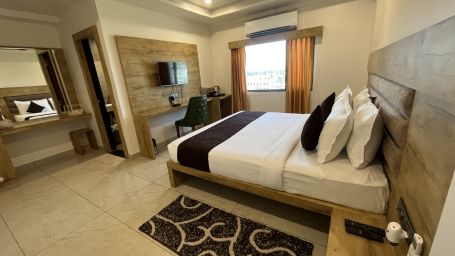 Side view of the Executive room with a cosy bed and a television mounted on the wall at Clarks Collection, Somnath