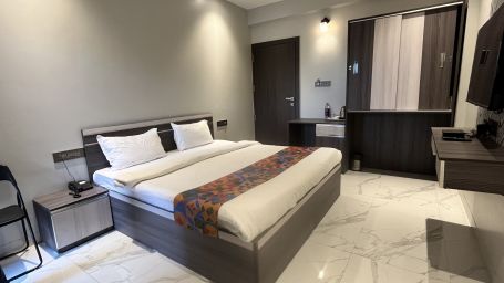 A hotel bedroom with a large bed with a head board, a night stand, a television and a cup board to the side- VITS Select Kharadi, Pune