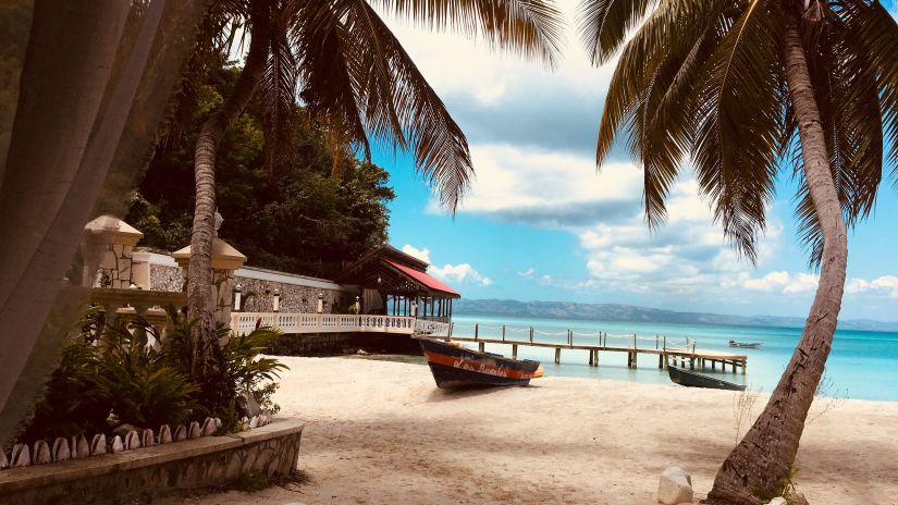 a boat beached on the side between palm trees