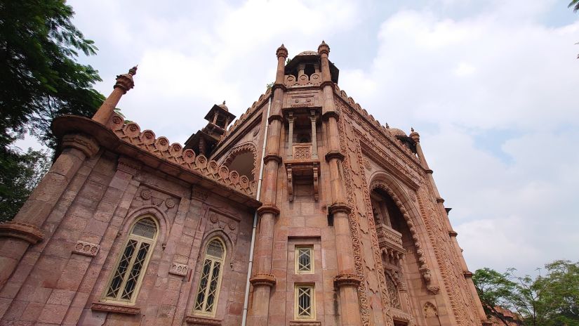 exterior facade of a church as seen from below with white clouds in the background