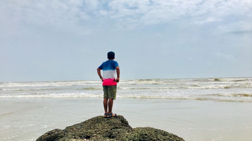 a person standing on a rock that is engulfed by algae on Mandrem Beach