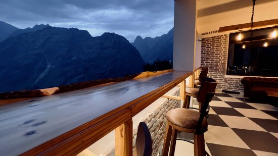 Wooden chairs positioned to overlook the misty hills afar in The Bourbon Club N Lounge at The Tattva Boutique Resort, Joshimath