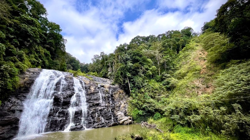 an overview of a waterfall with hills on either side and blue sky in the background