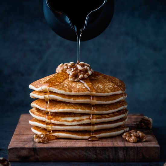 maple syrup being poured on pancakes