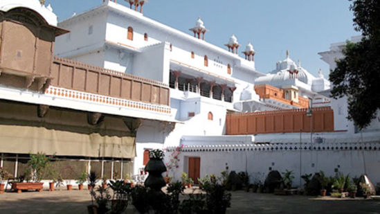 white brown building with a bunch of plants placed in front of it