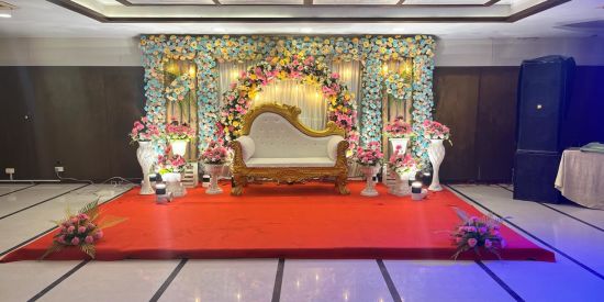 alt-text floral stage with red carpet and a diwan at the centre