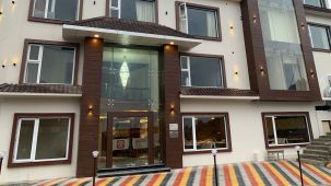 exterior of a hotel building that is shot from a lower angle during the day with a multicolour carpet on the floor near the entrance - 