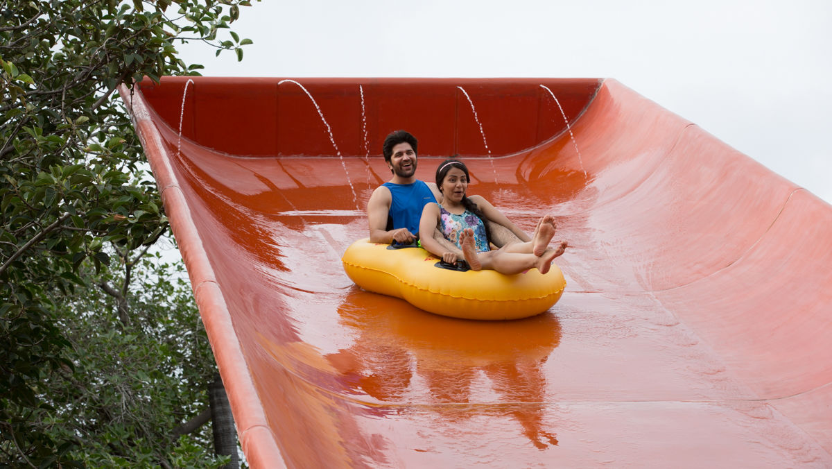 Man and woman sliding down a water slide in a yellow raft