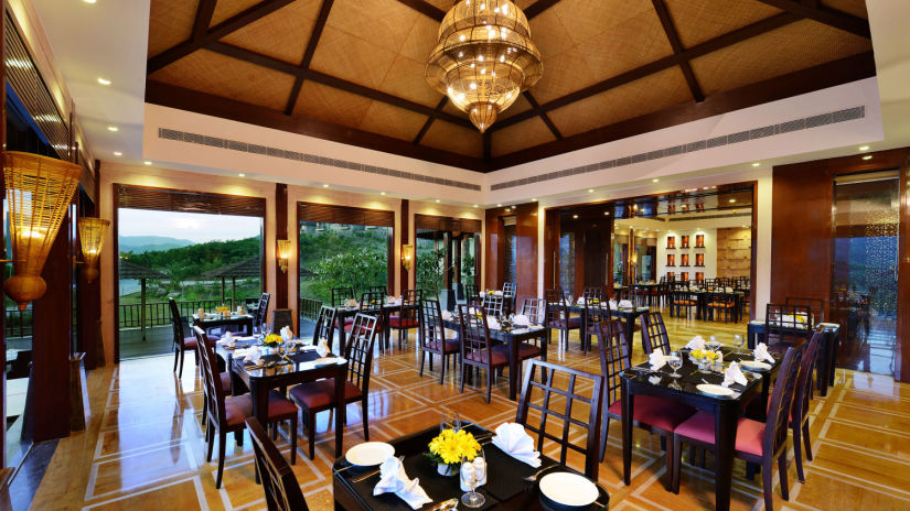 Seating arrangements at Oasis Restaurant with chandeliers on the roof- The Ananta Udaipur