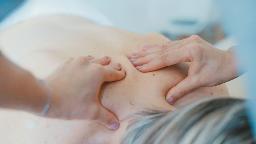 a woman at a spa laying on her stomach while a masseuse massages her back