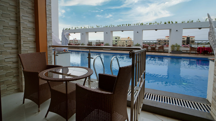 Seats in a balcony with a small table with views of the swimming pool inside one of the rooms - Shanti Seaview Resort & Spa