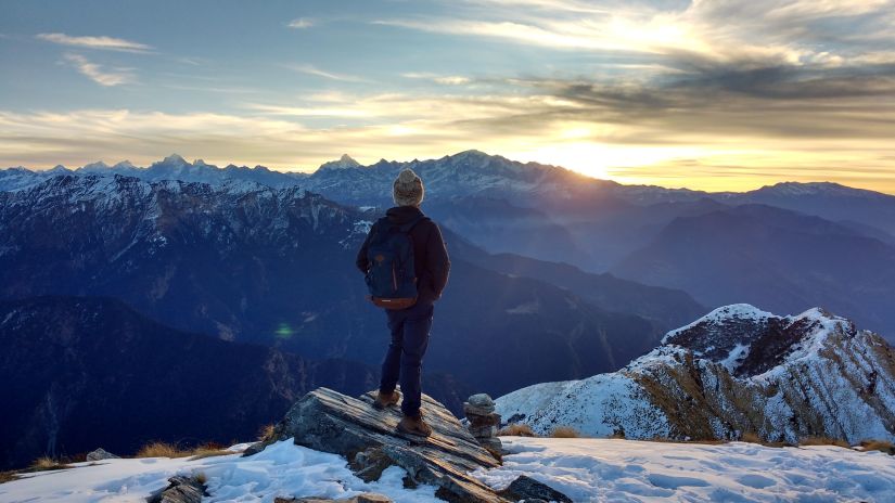 a person standing on a mountain cliff enjoying sunrise