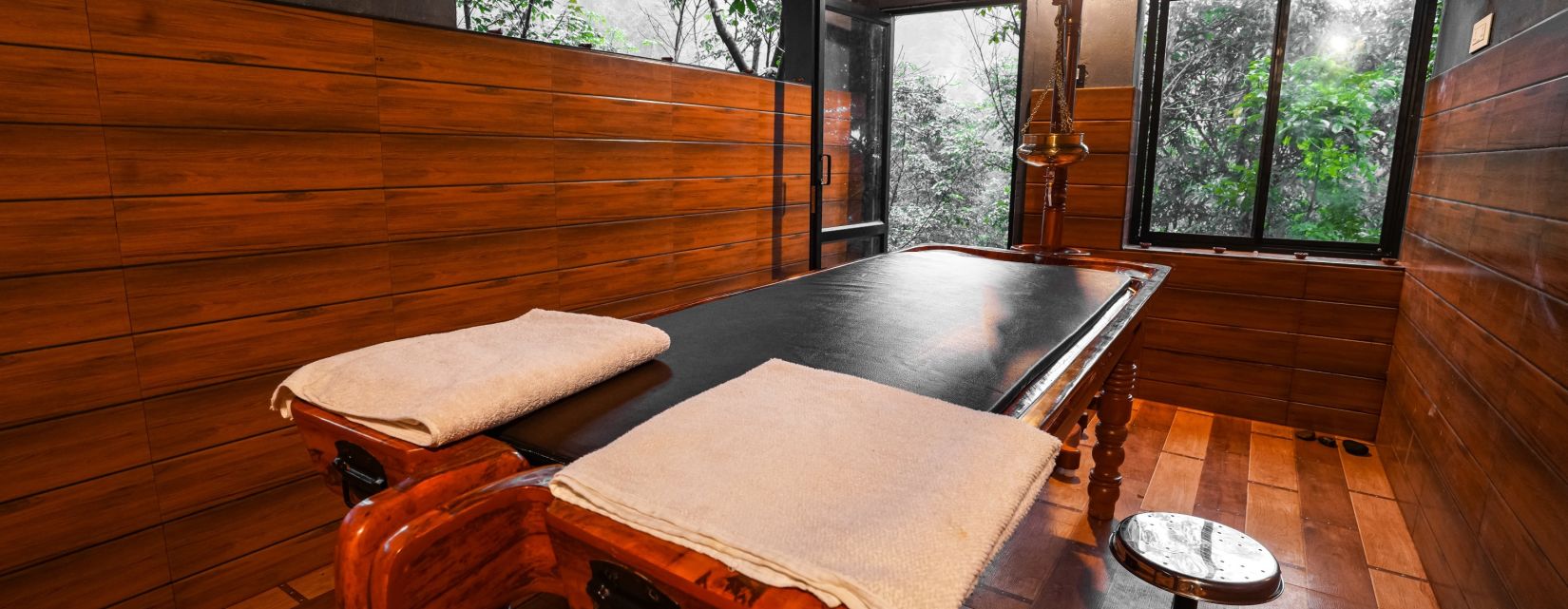 a wooden massage table inside the ayurvedic centre - Holistic Stay Eco Resort, Kannur