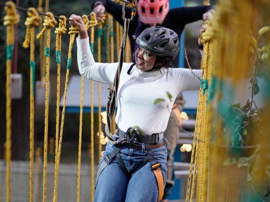 A woman walking on a Rope course at Themis Mudhouse - A Nature's Retreat Resort & Wellness