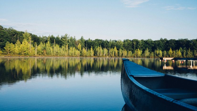 an overview of a lake with A boat in the foreground and forest cover in the background