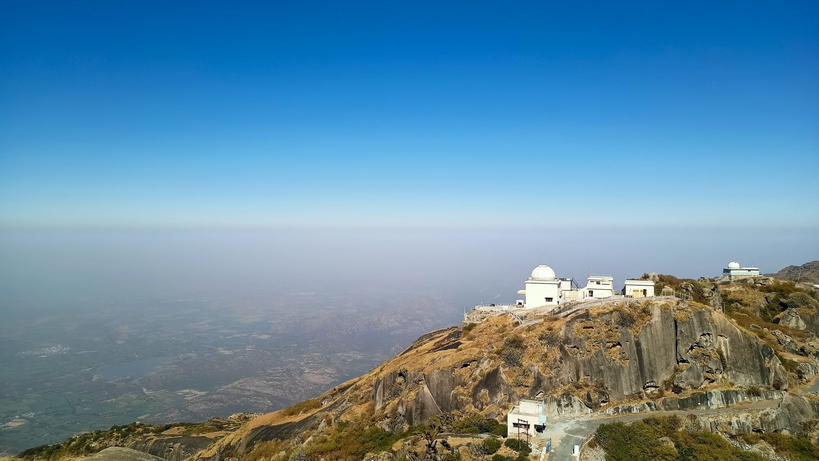 an aerial view of Mount Abu with a building on the top and blue sky in the background