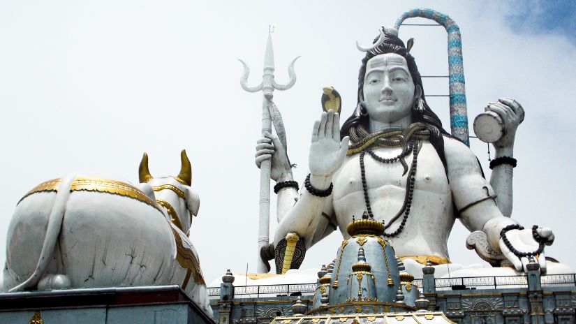 a huge statue of lord shiva built with stone and a sculpture of nandi - shot from a lower angle