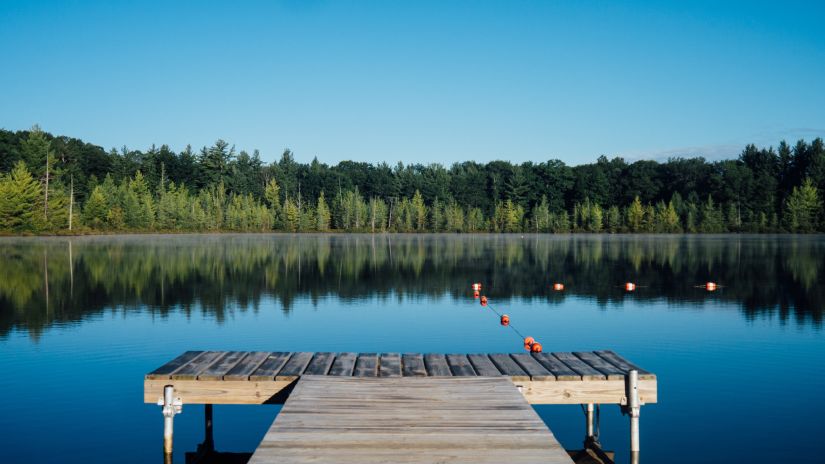 A woodern platform on a lake with trees in the background