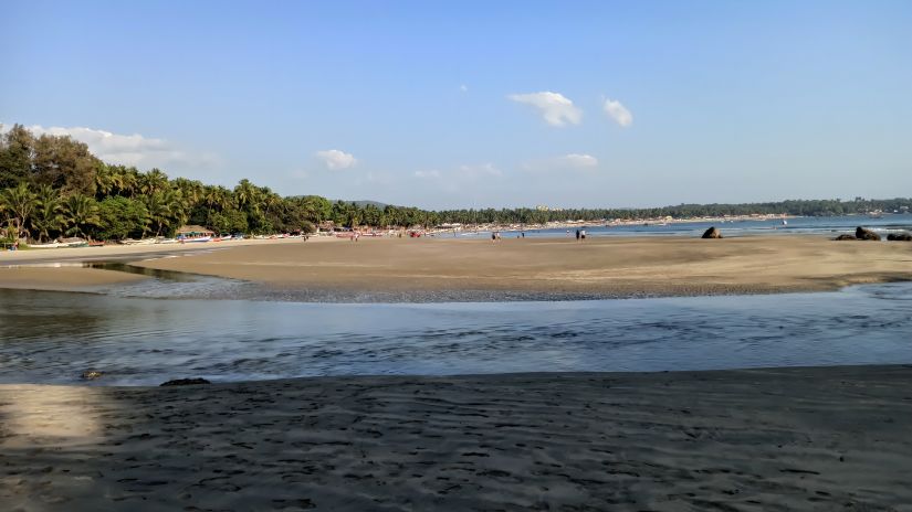 an overview of Palolem Beach in South Goa with greenery and blue skies in the background