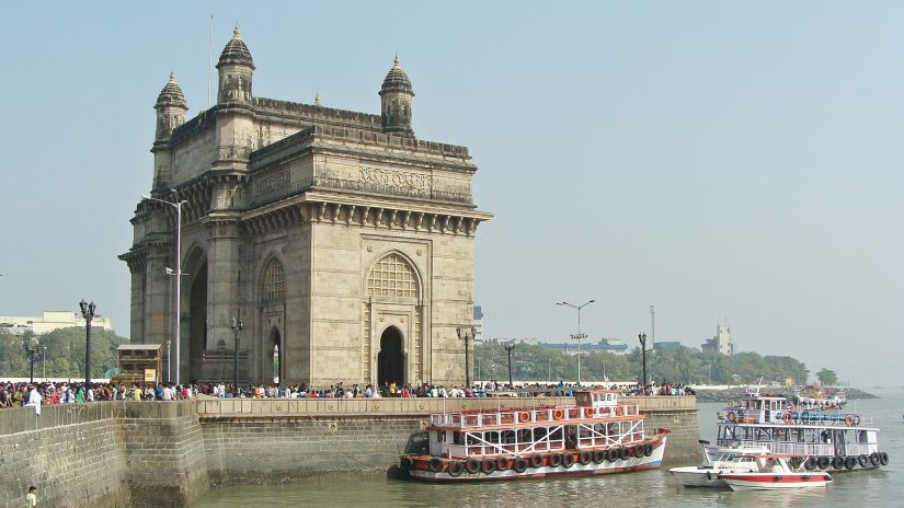 Getway of India, Mumbai,with boats in the harbour and people walking along the promenade