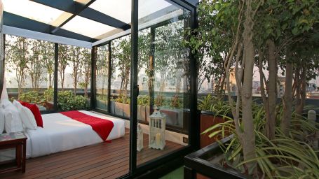 bedroom with glass windows next to potted plants in the terrace - Theory9 - Premium service apartments, bandra