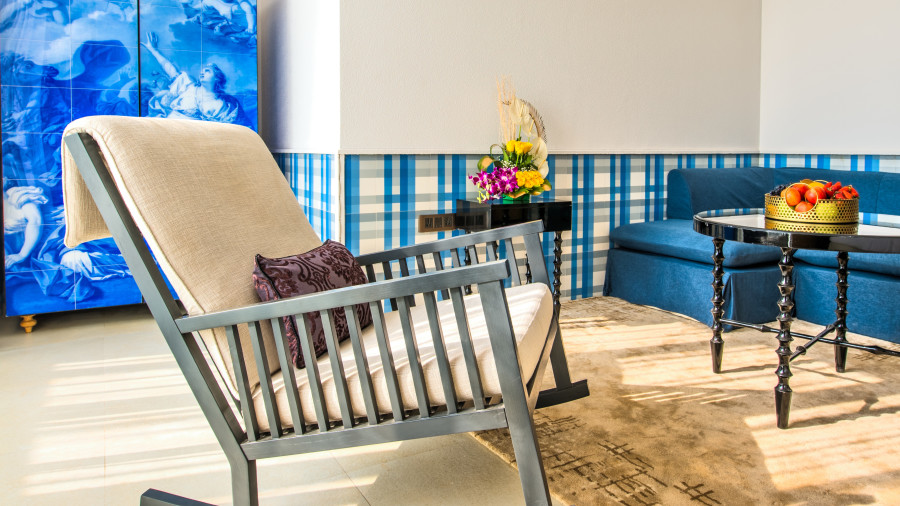 Rocking armchair with cushions near a table with a fruit platter and blue room background 