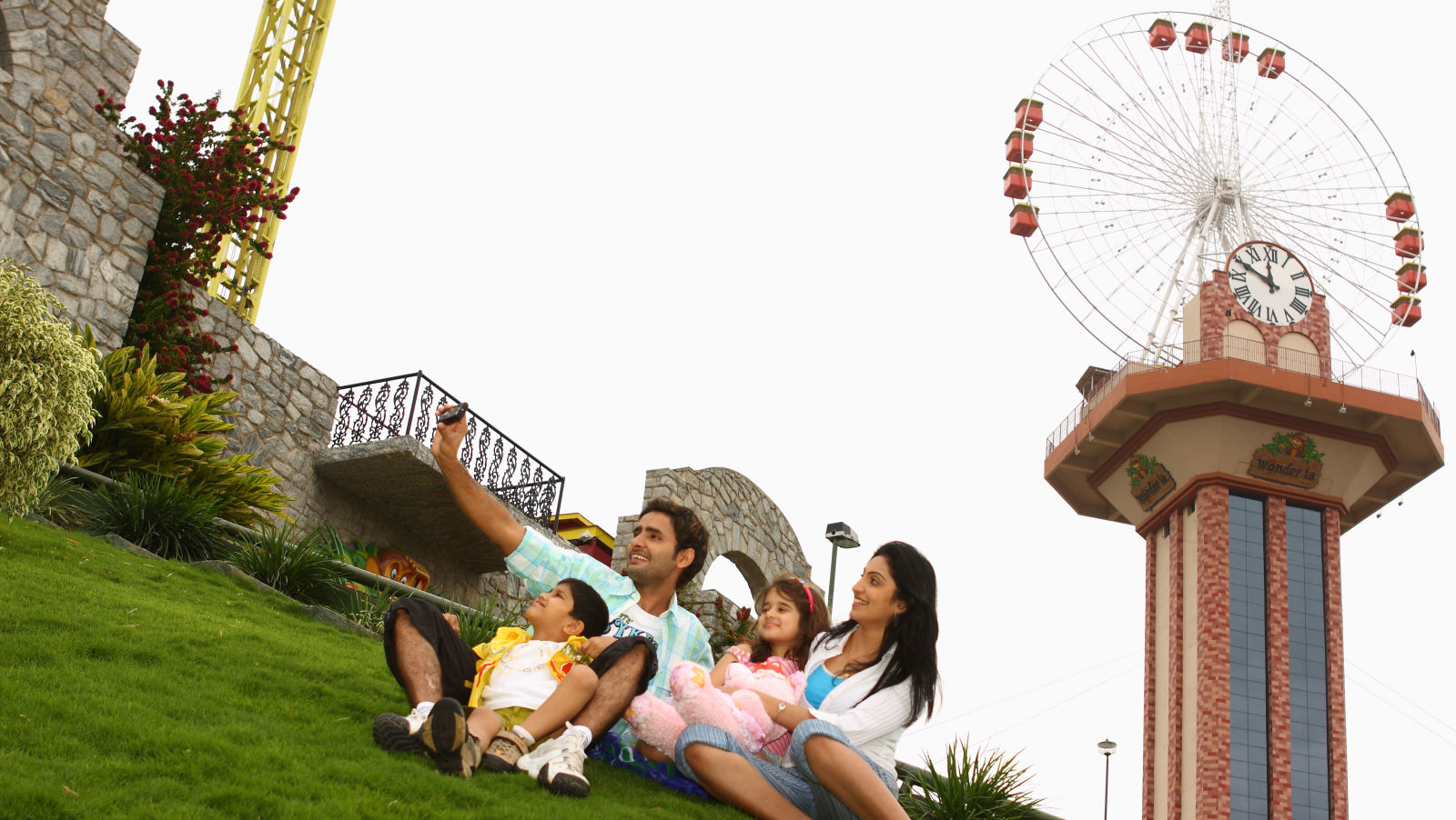 Family sitting on a lawn of grass with Sky wheel in the background