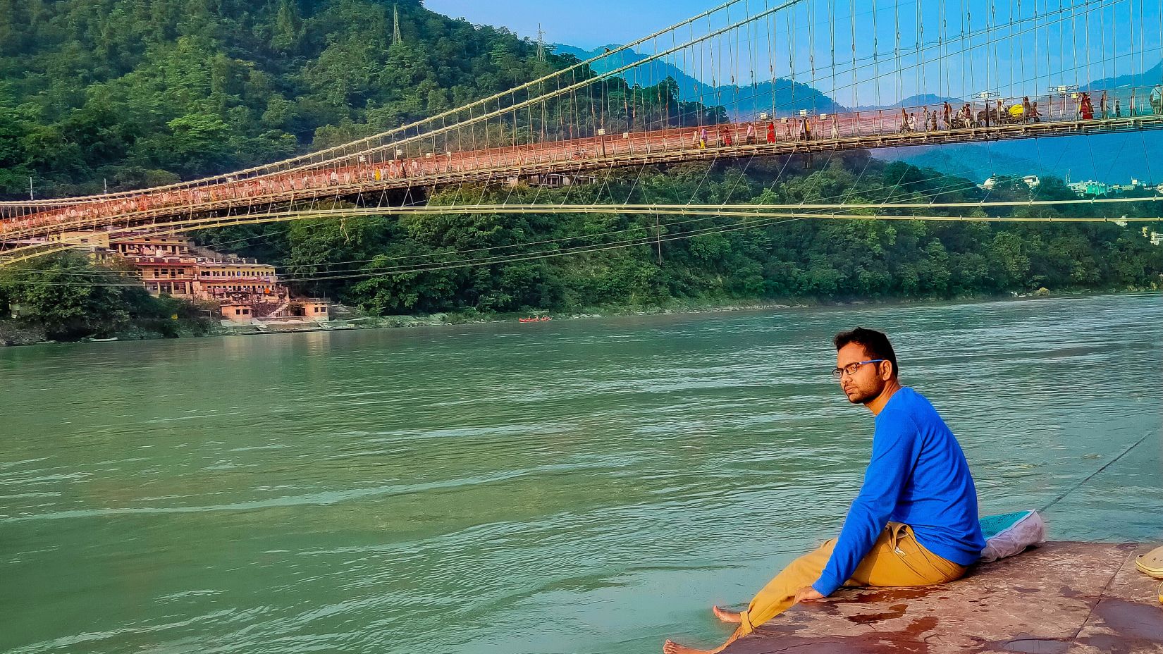 A man sitting on a ledge near Ram Jhula bridge @ Lamrin Boutique Cottages, Rishikesh