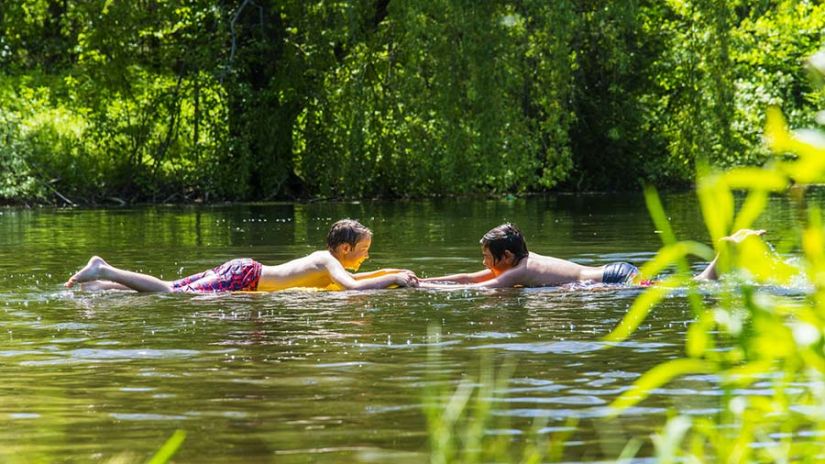 two kids floating on the river with forest cover in the background - Black Thunder, Coimbatore