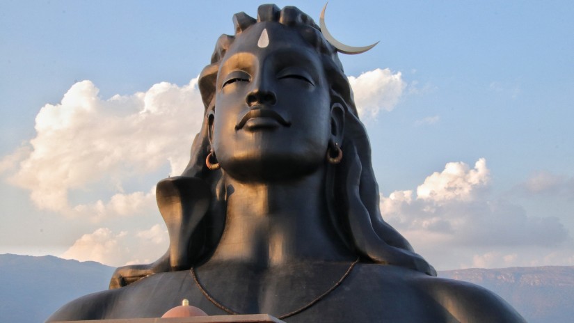 Statue of Lord Shiva with white clouds on blue sky in the background