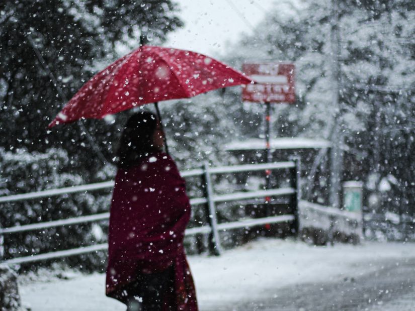 woman walking in snow with red umbrella