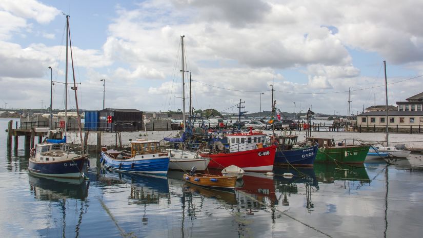 many Boats parked at a fishing harbour with blue sky in the background