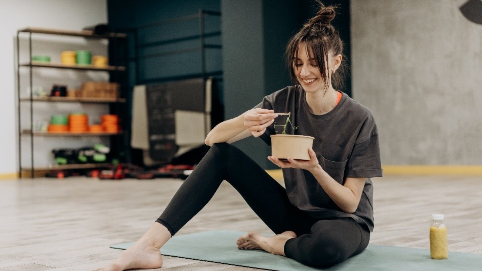 woman sitting on the floor and eating with a bowl