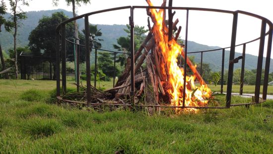 a bonfire inside metal casing area surrounded by green grass - Black Thunder, Coimbatore