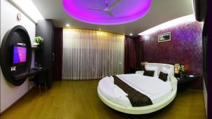 A round king bed with a tv wall mounted opposite the bed inside the Suite at VITS Select Grand Inn Ratnagiri