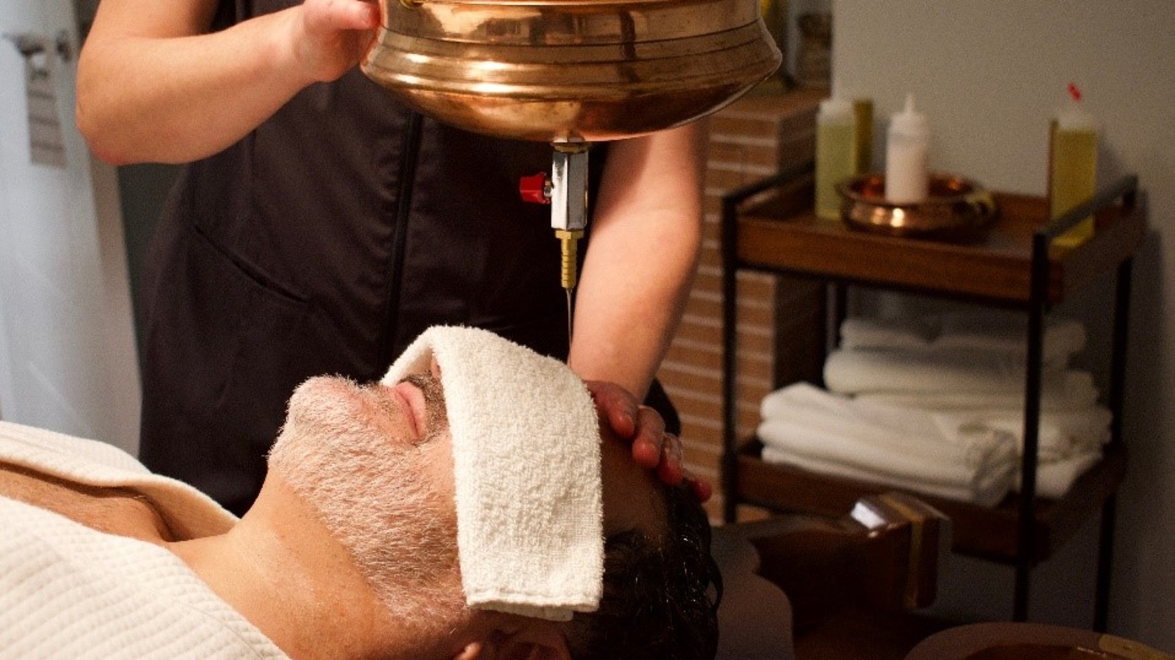 A man lying down on a table and receiving Ayurvedic treatment