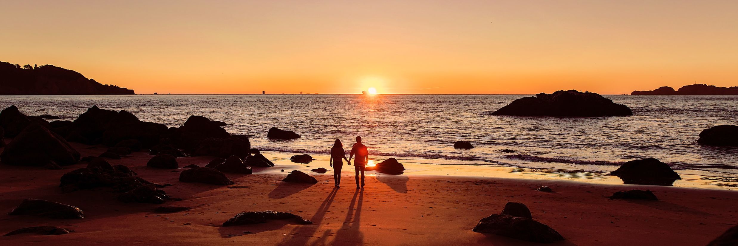 Couple standing on beach looking at sunset