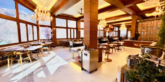 interior of Alpenrose Restaurant displaying wooden pillar and dining tables and chairs at The Tattva Boutique Resort, Joshimath