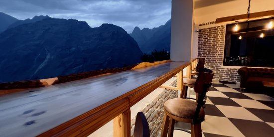 Wooden chairs positioned to overlook the misty hills afar in The Bourbon Club N Lounge at The Tattva Boutique Resort, Joshimath