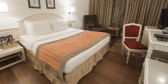 alt-text room with king size bed and wooden flooring at hotel bawa international