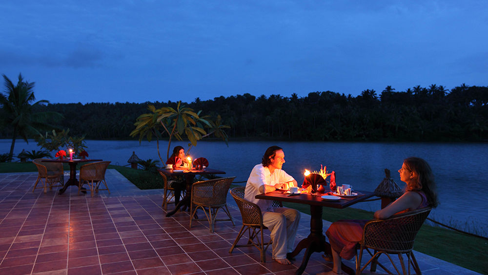 A couple enjoying dinner near the lake at Fragrant Nature Kollam