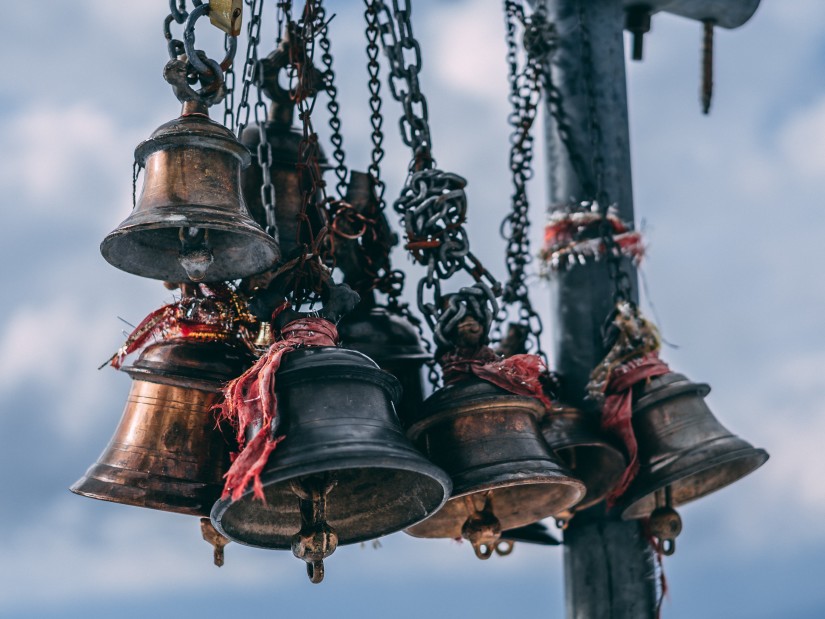 Ttemple bells with red sacred thread surrounding them