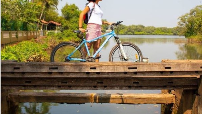 A person walking with a cycle on a bridge